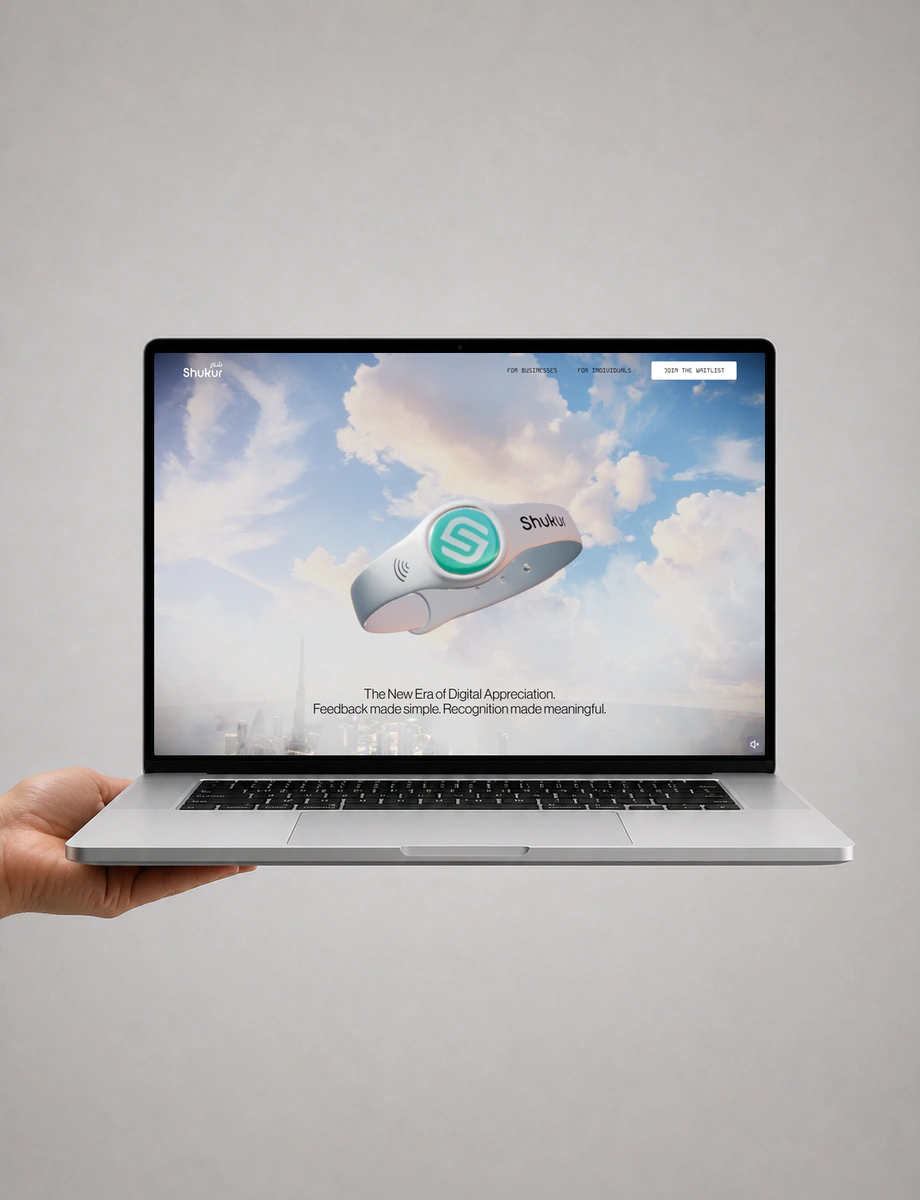 A hand supporting a front-facing silver laptop displaying Shukur’s optimistic waterfront city experience.
