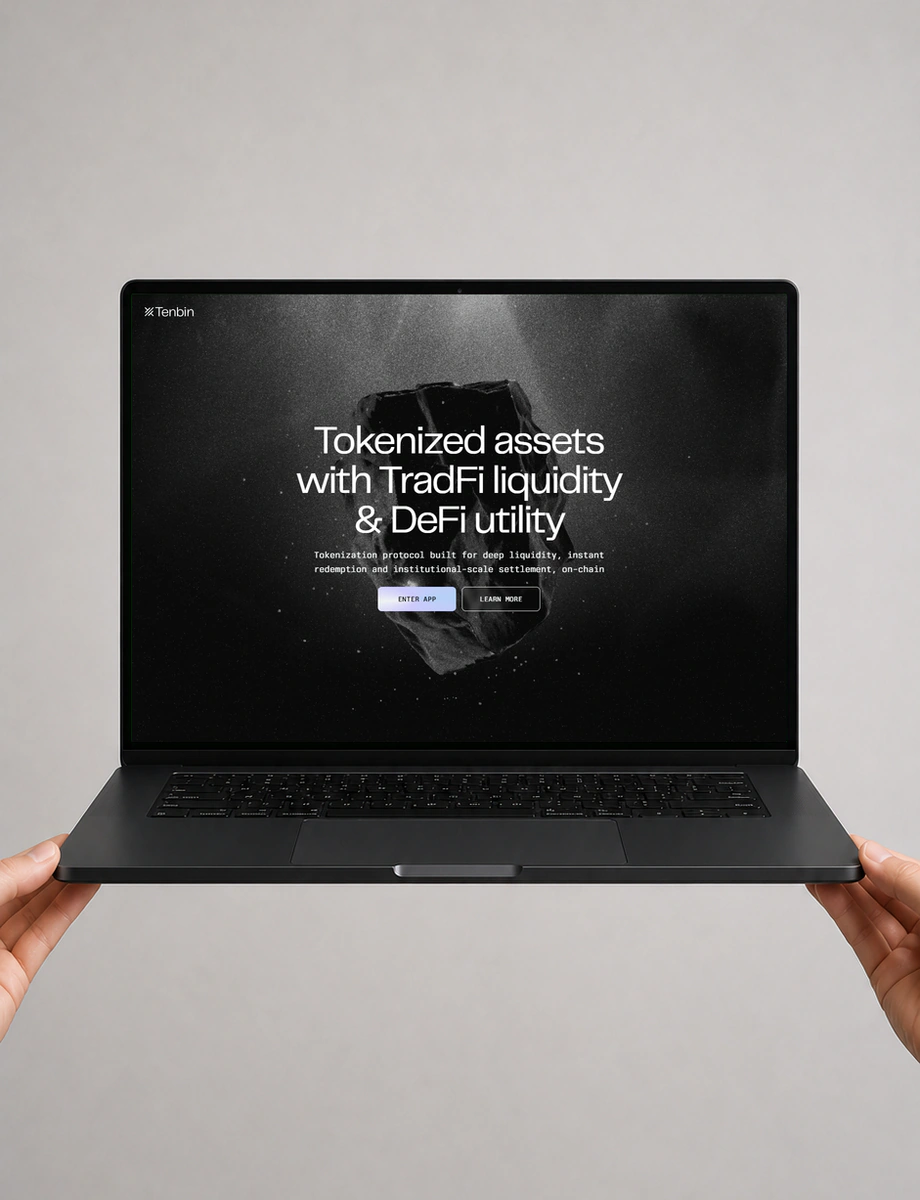 Two hands supporting a front-facing black laptop displaying the Tenbin tokenisation platform.